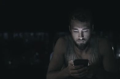 guy in dark texting on his phone