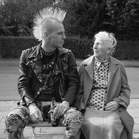 punk rocker sitting next to an old woman being kind