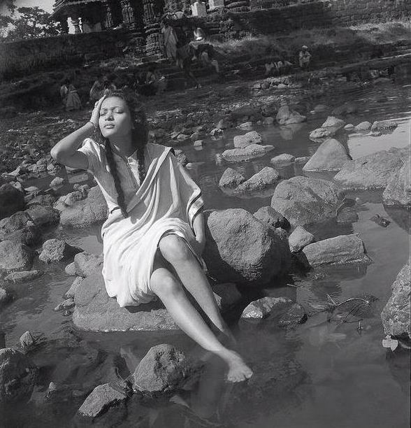 indian girl lying on a bed of rocks old photo