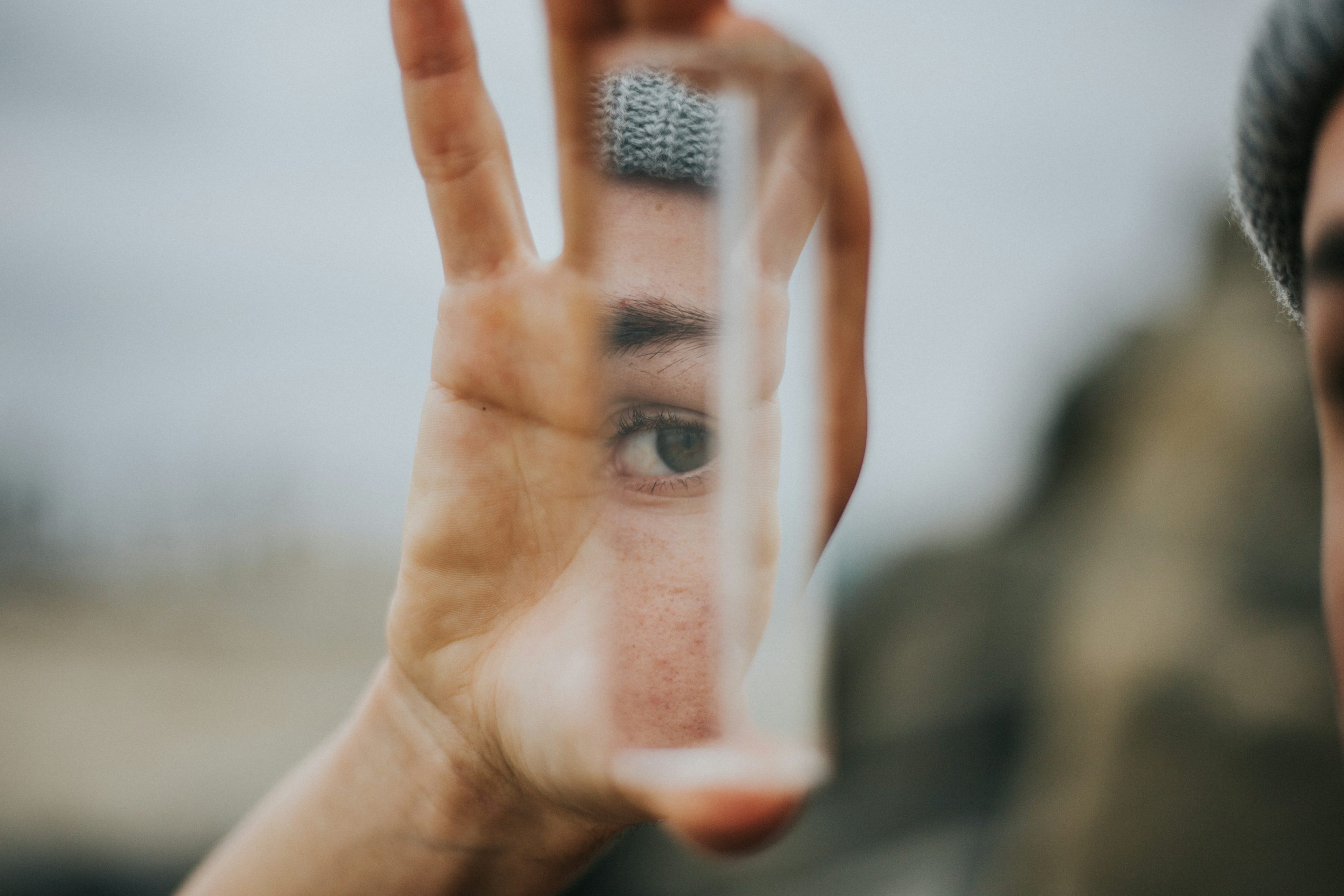 artsy photo of man holding up a mirror