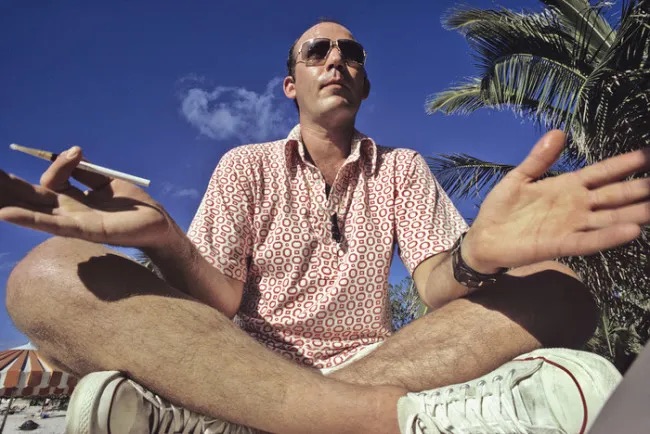 photo of hunter s thompson sitting on the ground smoking