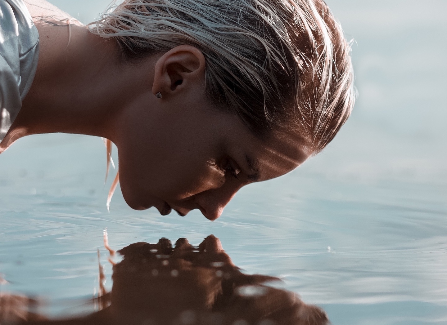 woman staring at her reflection in the water