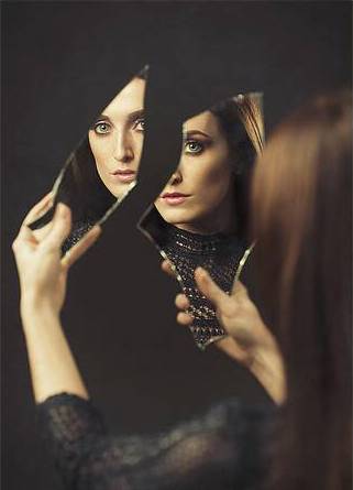 photo of woman looking into a broken mirror